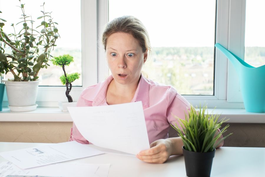 A woman being shocked by opening her high electric bill.